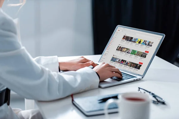 Vista cortada da mulher usando laptop com site do youtube na tela na mesa de escritório — Fotografia de Stock