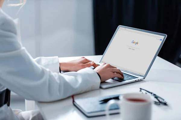 Ausgeschnittene Ansicht einer Frau mit Laptop und Google-Website auf dem Bildschirm am Schreibtisch — Stockfoto