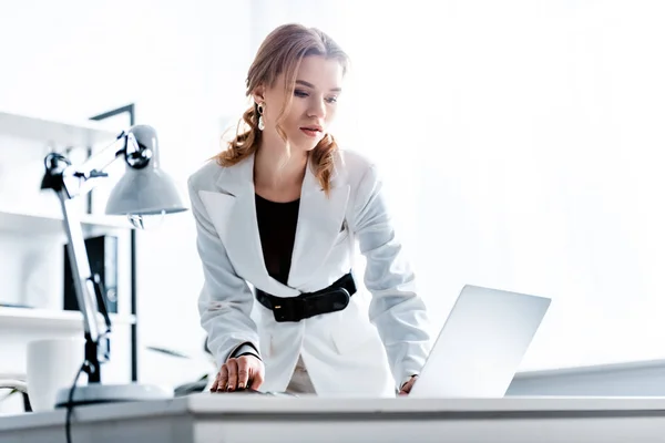 Empresaria concentrada en ropa formal usando portátil en el lugar de trabajo - foto de stock
