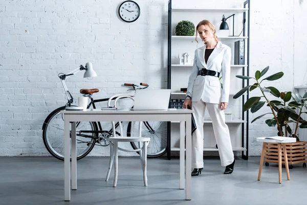 Élégante femme d'affaires en tenue formelle regardant la caméra dans l'intérieur de bureau moderne — Photo de stock