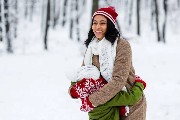 Smiling african american mother embracing daughter in winter park — Stock Photo
