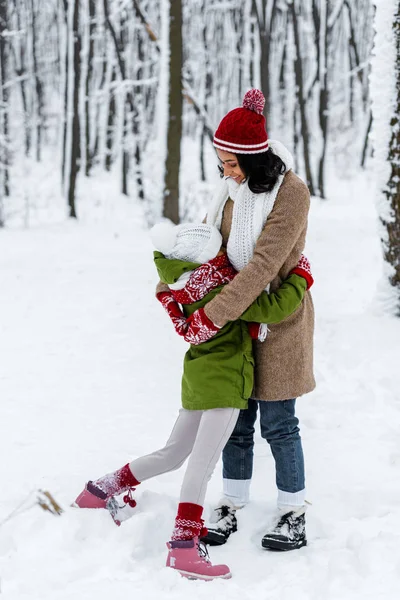 Sorridente mamma afro-americana che abbraccia la figlia nel parco invernale — Foto stock