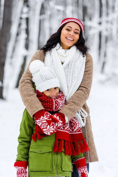 Sorridente afro-americano mãe e filha olhando para câmera no parque de inverno — Fotografia de Stock