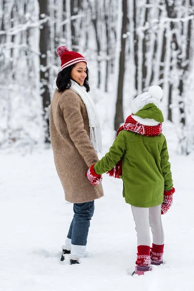 Afro-américaine mère et fille préadolescente tenant la main et se regardant dans le parc d'hiver — Photo de stock