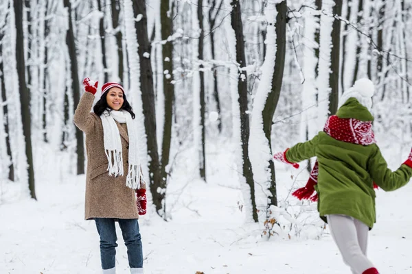 Alegre afro-americana mãe jogando bolas de neve com a filha no parque de inverno — Fotografia de Stock