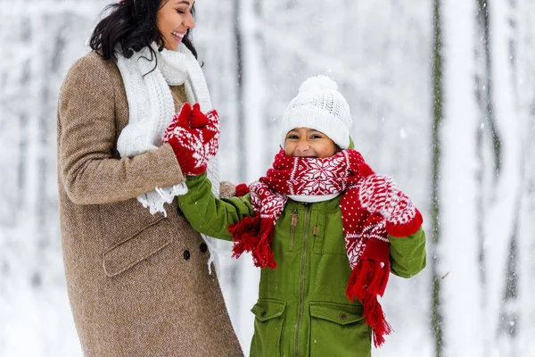 Усміхнена афро-американська мама тримає руку веселої дочки в зимовому парку — стокове фото