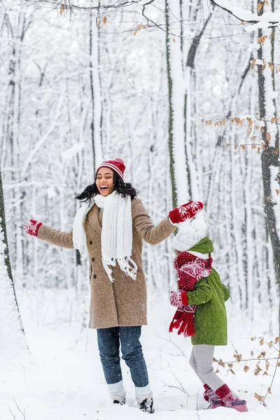 Attraktive afrikanisch-amerikanische Frau lächelt und hat Spaß mit niedlichem Kind im Winterpark — Stockfoto