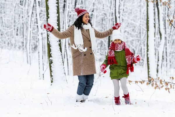 Hermosa mujer afroamericana y linda hija preadolescente divirtiéndose en el parque de invierno - foto de stock