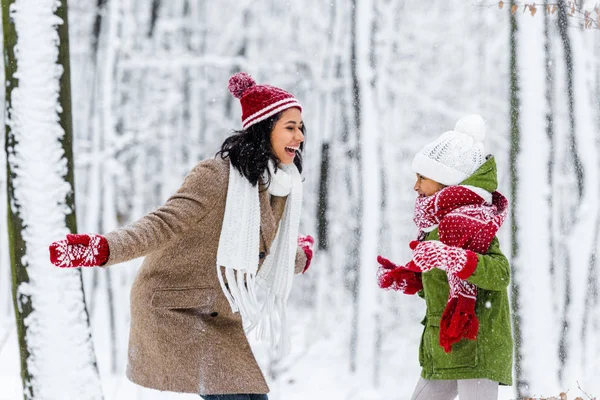 Beautiful african american woman and cute preteen daughter laughing and looking at each other in winter park — Stock Photo