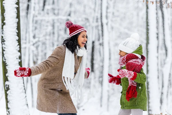 Schöne afrikanisch-amerikanische Frau und süße preteen Tochter lachen und schauen einander im Winterpark an — Stockfoto