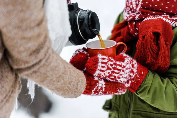 Vue recadrée de mère verser le thé dans la tasse rouge de thermos — Photo de stock