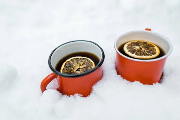 Tazas rojas de té con limón en la nieve - foto de stock