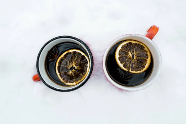 Dos tazas de té con limones sobre nieve blanca - foto de stock