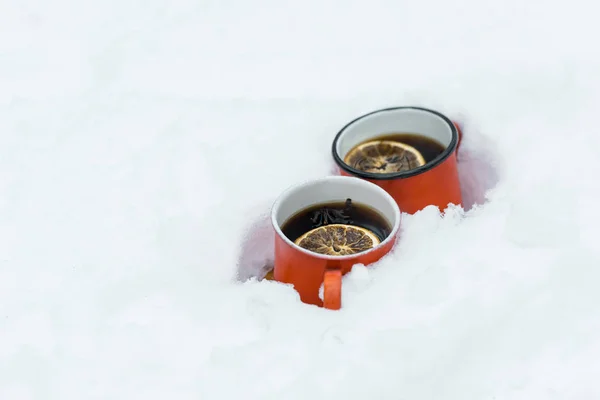 Dos tazas de té rojo con rodaja de limones de pie en el bosque nevado - foto de stock