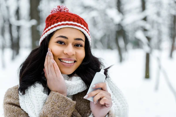 Attractive african american woman touching cheek in winter forest — Stock Photo