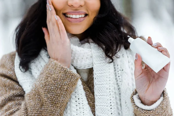 Mujer afroamericana tocando mejilla y aplicando crema protectora - foto de stock