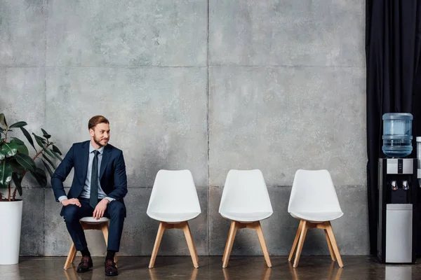 Homem de negócios bonito elegante em terno sentado na sala de espera — Fotografia de Stock