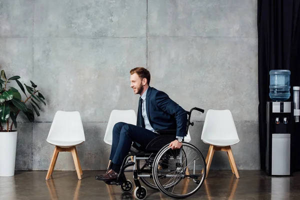 Hombre de negocios en ropa formal sentado en silla de ruedas en la sala de espera - foto de stock