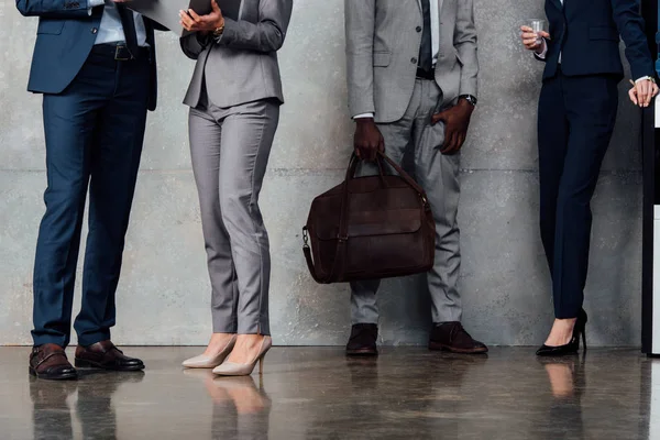 Cropped view of stylish businesspeople in formal wear in waiting hall — Stock Photo
