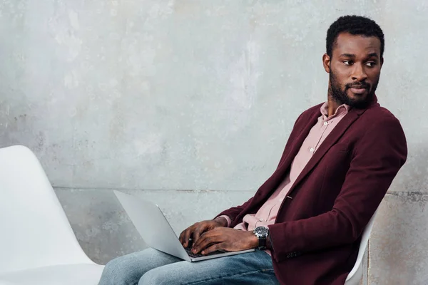 African american casual businessman using laptop on grey background with copy space — Stock Photo