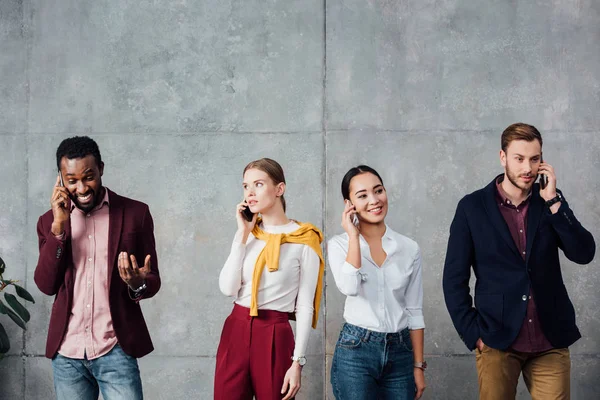 Multiethnic casual businesspeople talking on smartphones in waiting hall — Stock Photo