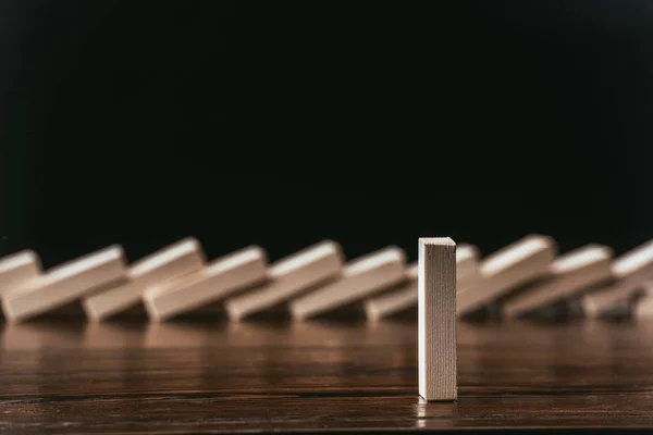 Selective focus of wooden block with fallen bricks row on background isolated on black — Stock Photo