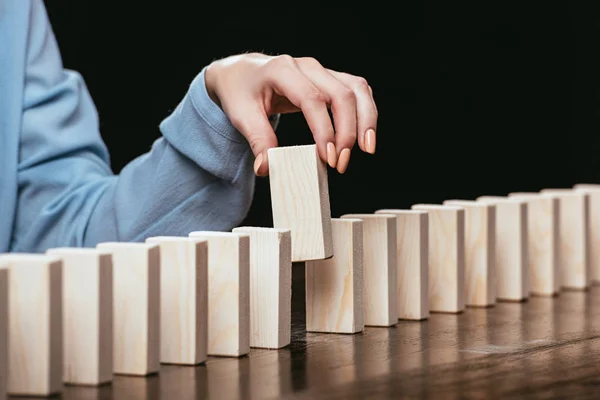 Vue recadrée de la femme cueillant la brique de bois de la rangée de blocs isolés sur noir — Photo de stock