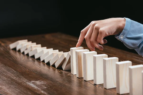 Vista recortada de la mujer evitando que los bloques de madera caigan aislados en negro — Stock Photo