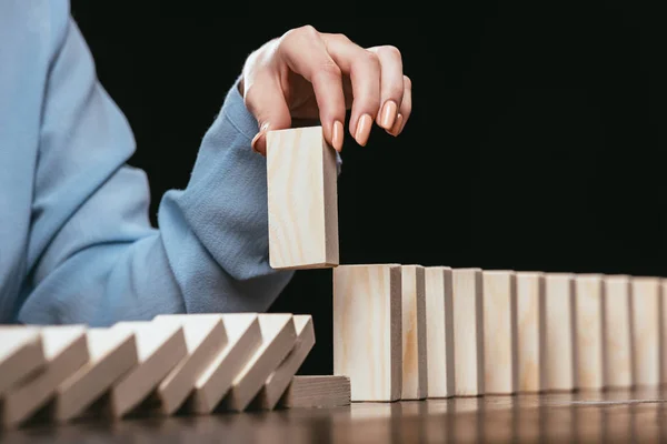 Vue partielle de la femme ramassant la brique de bois de la rangée de blocs isolés sur noir — Photo de stock