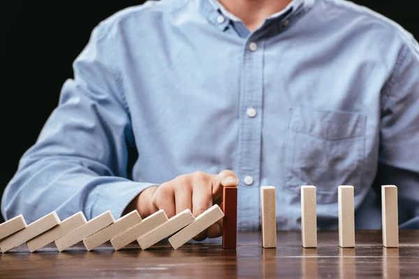 Partial view of man touching red brick and preventing wooden blocks from falling — Stock Photo