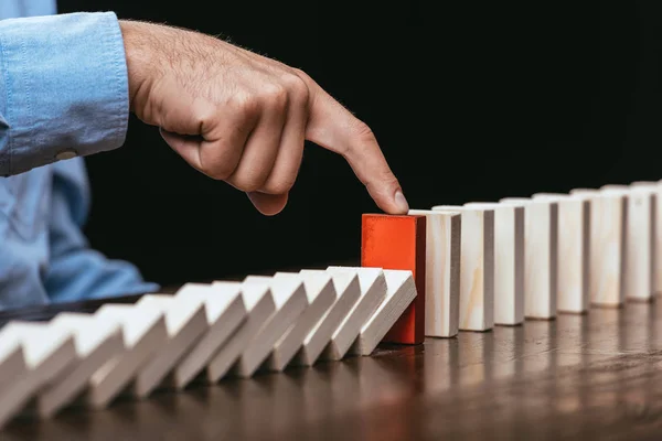 Partial view of man touching red brick and preventing wooden blocks from falling — Stock Photo