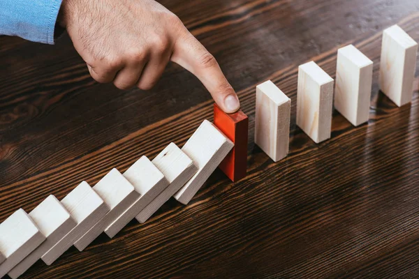 Cropped view of man touching red brick and preventing wooden blocks from falling — Stock Photo