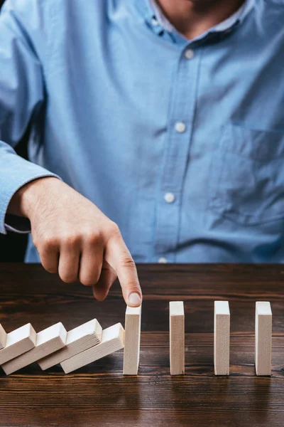 Vista recortada del hombre evitando que los bloques de madera caigan con el dedo — Stock Photo