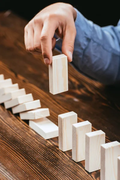 Selective focus of man picking wooden brick out of row on wooden table — Stock Photo