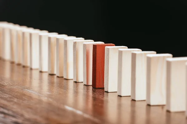 Row of wooden blocks with red one on desk isolated on black — Stock Photo