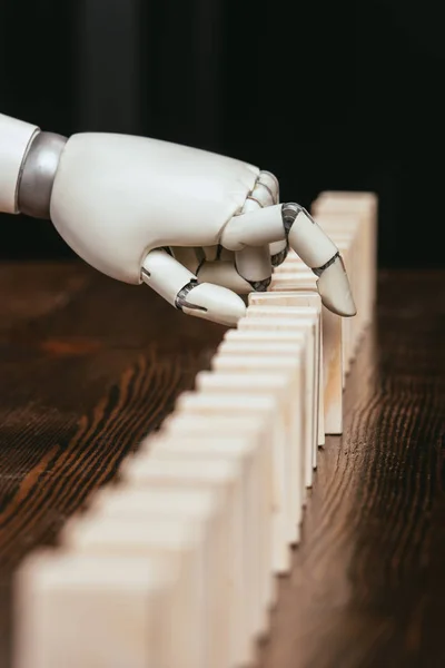 Selective focus of robotic hand picking wooden brick from row of blocks on desk — Stock Photo