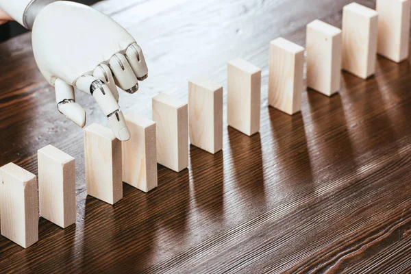 Robotic hand picking wooden brick from row of blocks on desk with copy space — Stock Photo