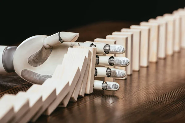 White robotic hand preventing wooden blocks from falling on desk — Stock Photo