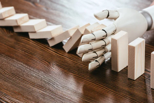 Роботизированная рука, предотвращающая падение деревянных блоков на стол с копировальным пространством — стоковое фото