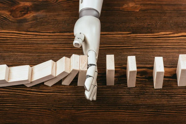 Robotic hand preventing wooden blocks from falling on desk — Stock Photo