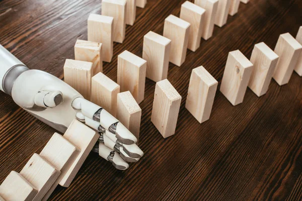 Mano robótica evitando que los bloques de madera caigan sobre el escritorio — Stock Photo