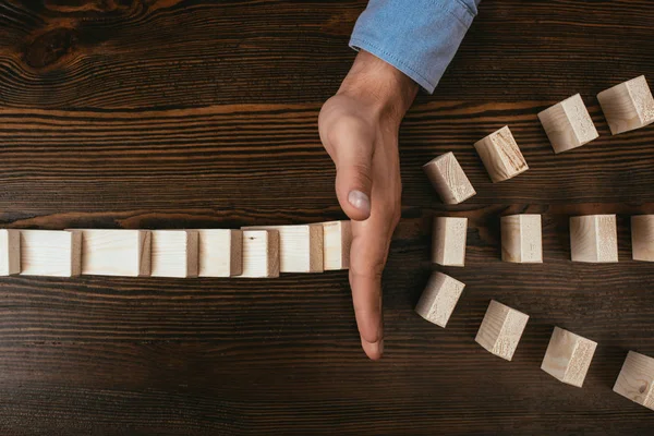 Top view of woman at desk preventing wooden blocks from falling — Stock Photo