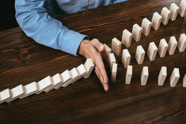 Cropped view of man at desk preventing wooden blocks from falling — Stock Photo