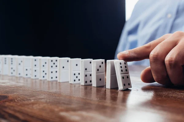 Close up view of man pushing domino row on wooden desk — Stock Photo