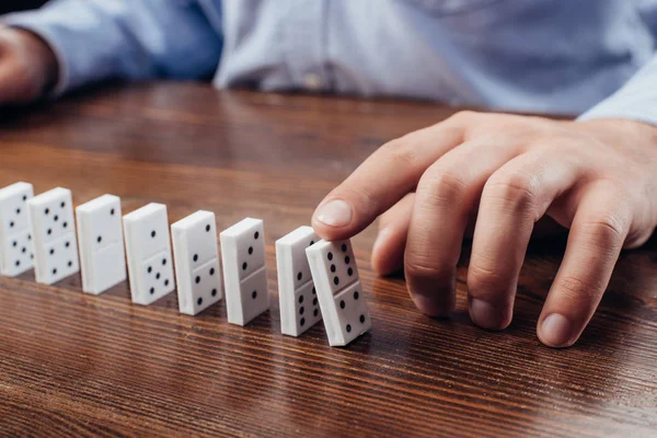 Teilansicht eines Mannes, der Domino-Reihe auf Holztisch schiebt — Stockfoto