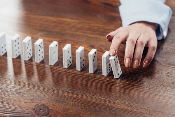 Vista cortada da mulher empurrando linha de dominó na mesa de madeira com espaço de cópia — Fotografia de Stock