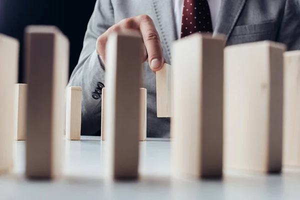 Selective focus of man picking wooden brick from row of blocks on desk — Stock Photo