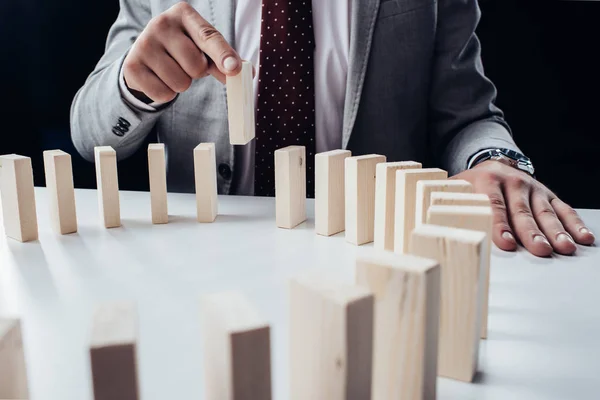 Vue partielle de l'homme cueillant la brique de bois du cercle de blocs sur le bureau — Photo de stock