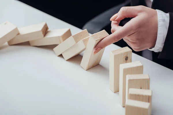 Close up view of woman preventing wooden blocks from falling — Stock Photo