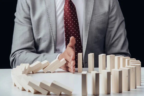 Partial view of businessman preventing wooden blocks from falling — Stock Photo